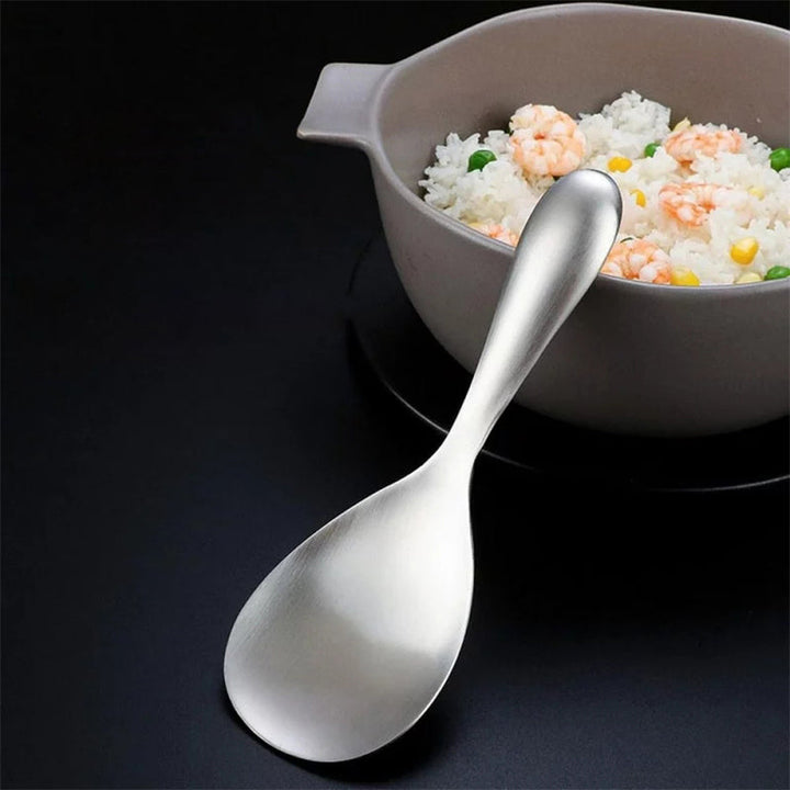 Cooking with a non-stick stainless steel rice spoon, perfect for serving fluffy rice