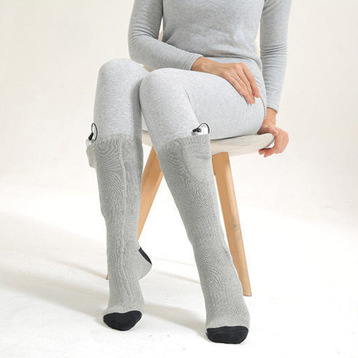 Unisex electric heated socks next to a snowboard, ready for winter sports and snow.
