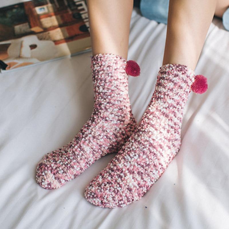 Pair of fluffy cupcake slipper socks for women, pink with white frosting detail, on a clean background.