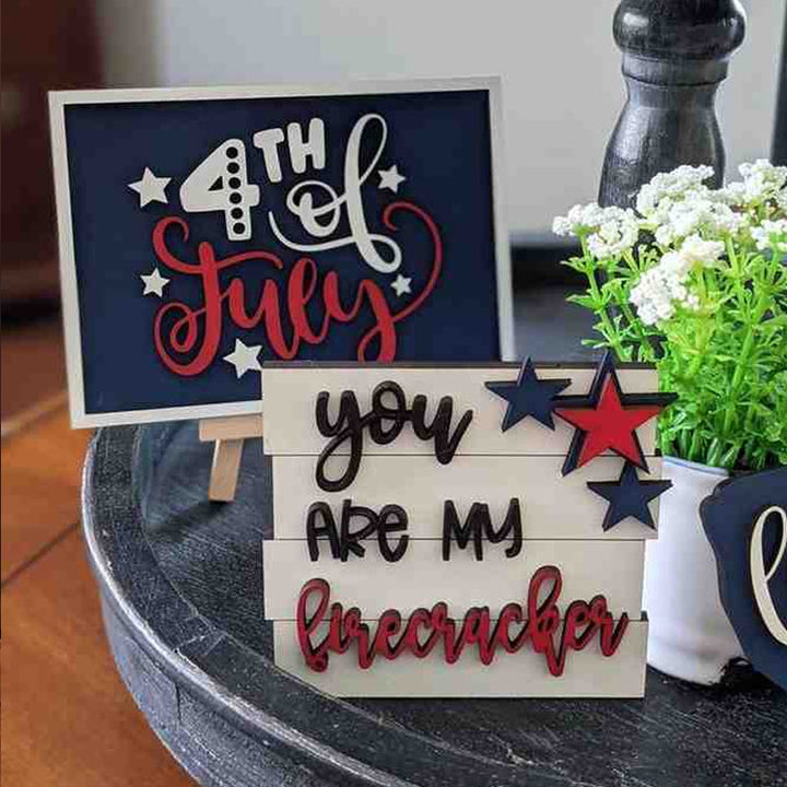 Closeup of a 'God Bless America' sign & wooden star from a patriotic tiered tray decor set.