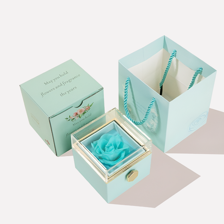 Close-up of an engraved silver heart necklace with personalized text, part of a preserved rose gift set.