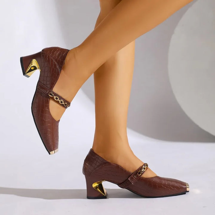 Women's red block heel pumps from the front, exhibiting the modern squared toe and chain ornament.