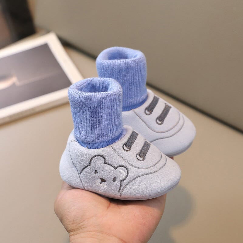 Side profile of a plush baby bootie, showing its soft material and sole