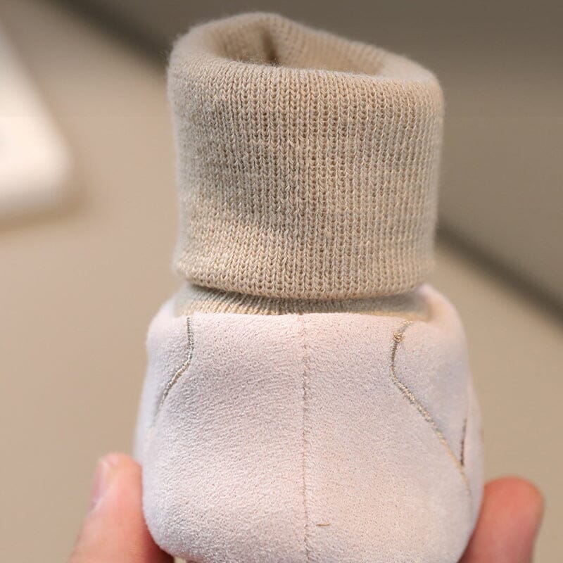 Baby crawling happily while wearing soft sole plush winter booties