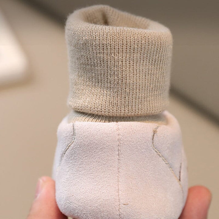 Baby crawling happily while wearing soft sole plush winter booties