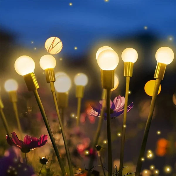 Solar-powered LED firefly garden lights swaying gently in a landscaped path at dusk