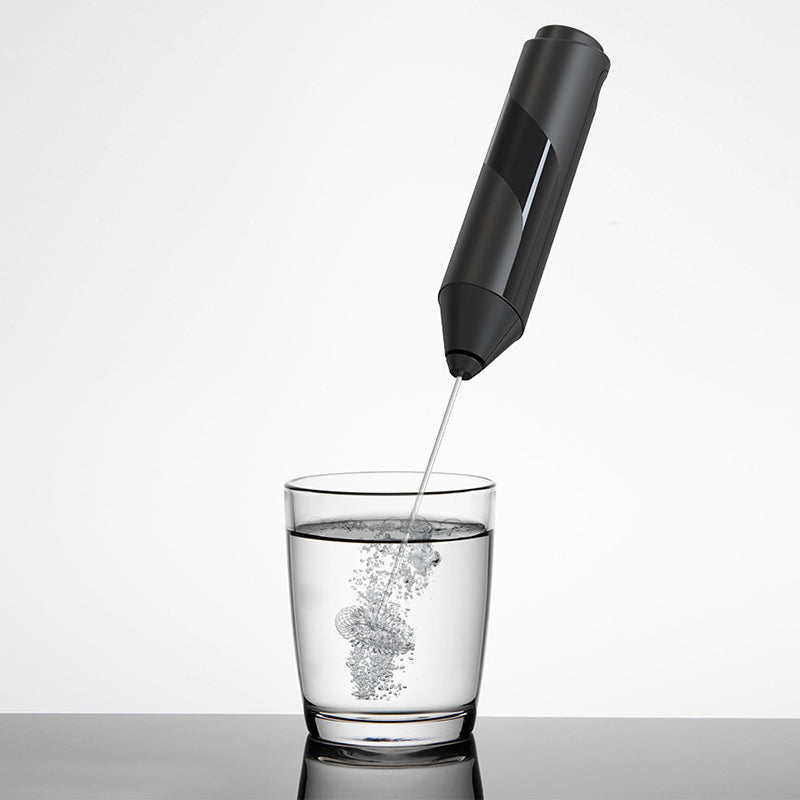 Handheld milk frother displayed with its stand against a clean kitchen background