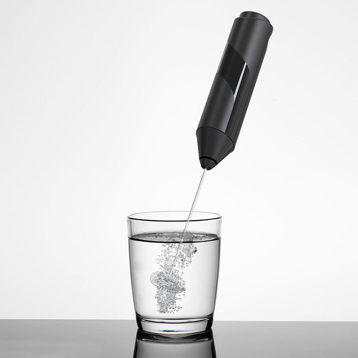 Handheld milk frother displayed with its stand against a clean kitchen background