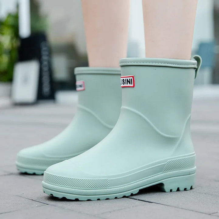Stylish black women's waterproof ankle rain boots, slip-on design for wet weather puddle protection.