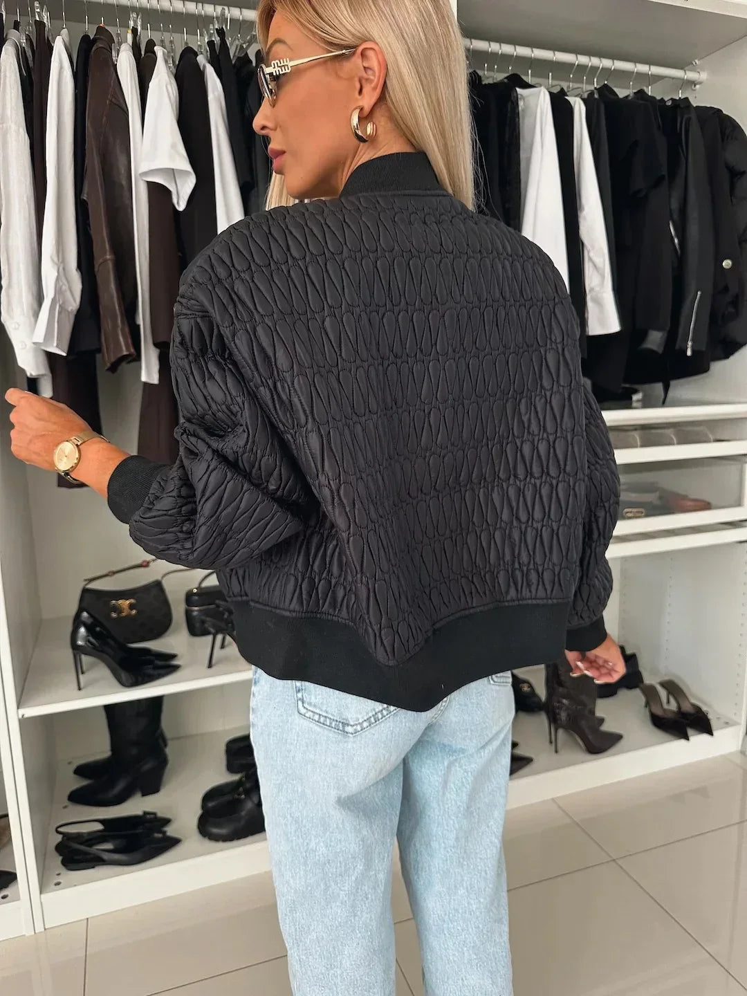 Side view of a women's quilted bomber jacket, highlighting its stylish cut