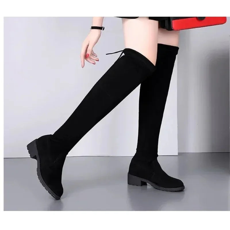 Close-up of the block heel on women's black thigh-high boots, highlighting texture