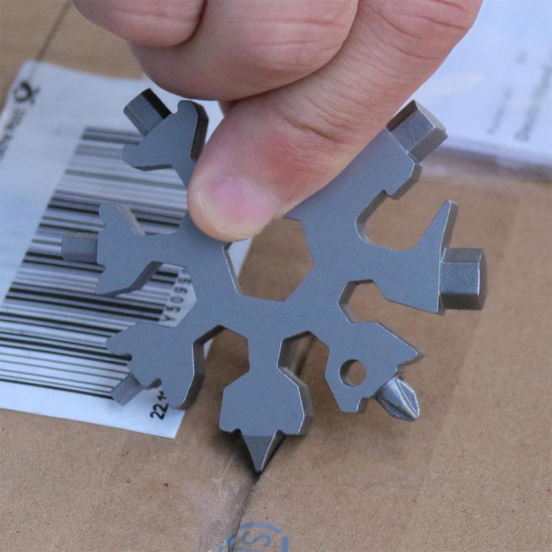 Close-up of a snowflake multi-tool keychain in hand, demonstrating its compact size and utility