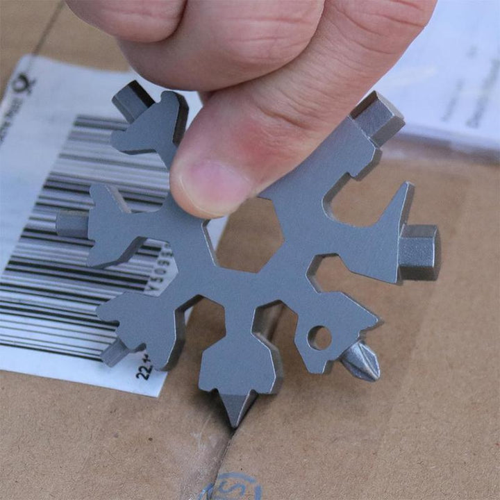 Close-up of a snowflake multi-tool keychain in hand, demonstrating its compact size and utility