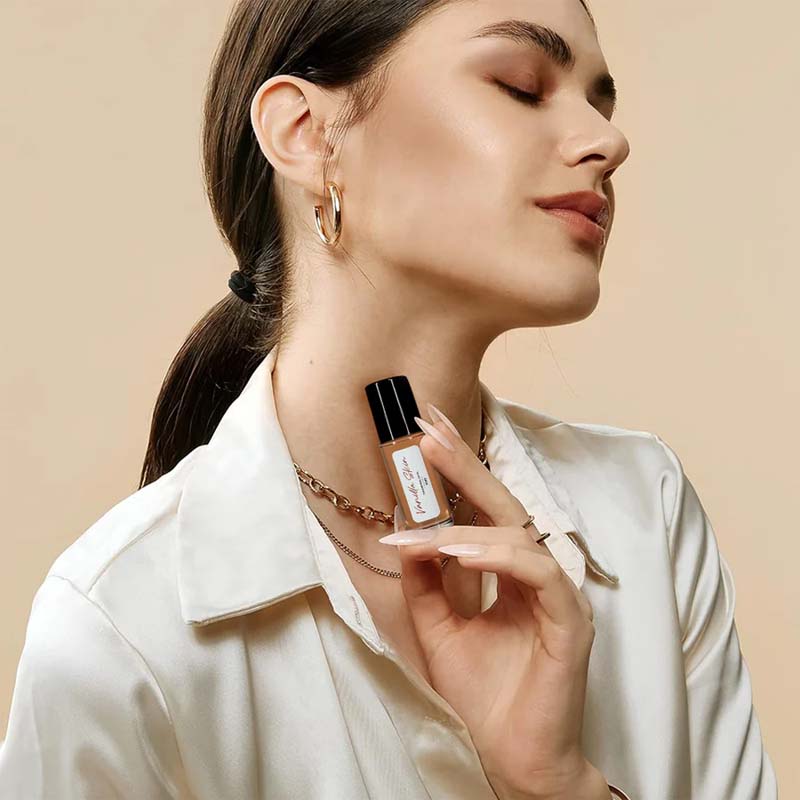 Botanical illustration of peach and vanilla alongside the Captivating Roll-On Fragrance Oil bottle, emphasizing natural scents.