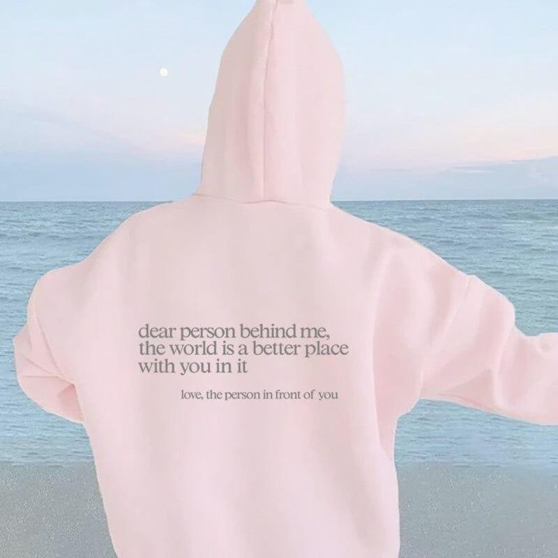 Person relaxing in bed wearing 'Dear Person Behind Me' inspirational sweatshirt