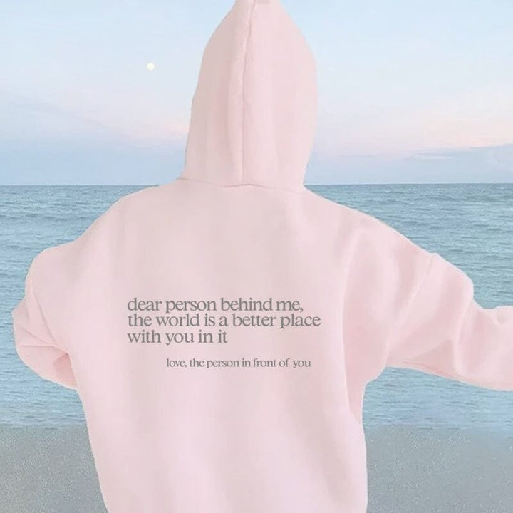 Person relaxing in bed wearing 'Dear Person Behind Me' inspirational sweatshirt