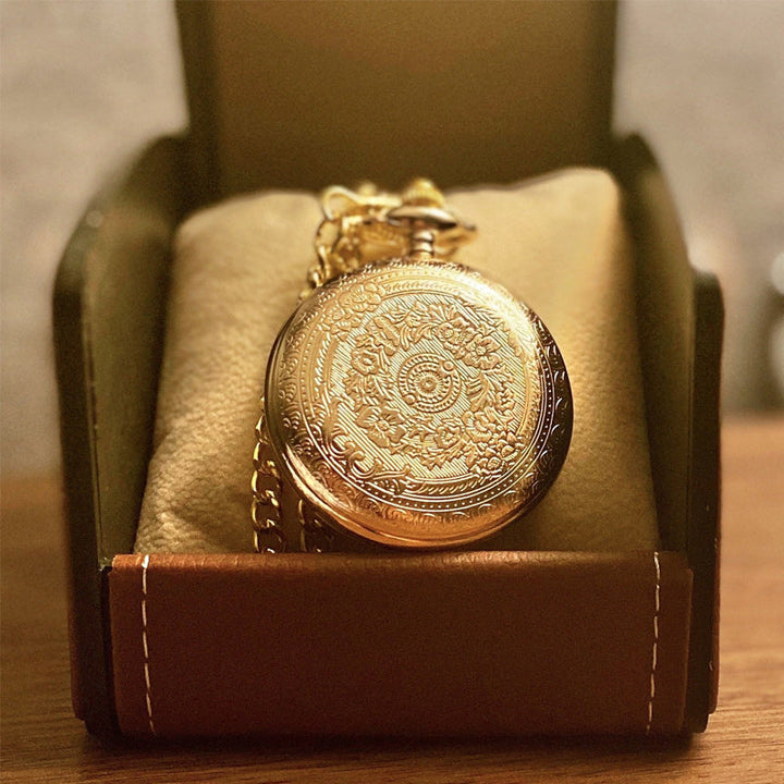 Close-up of a decorative gold engraved quartz pocket watch face with Roman numerals