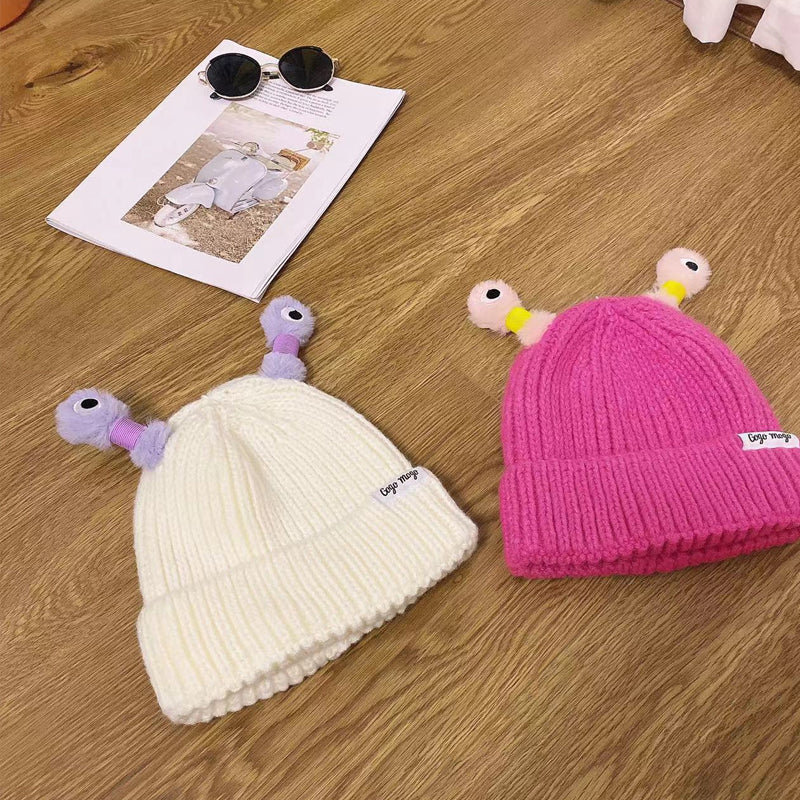 Side profile of a pink Monster Beanie, featuring embroidered monster eyes