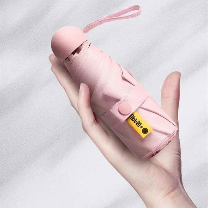 Small-sized foldable umbrella next to a smartphone, highlighting its mini portable design