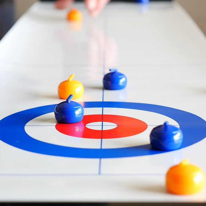 Indoor sports game: tabletop curling set with an easy-to-store mat, two magnetic launchers, and eight gliding stones.