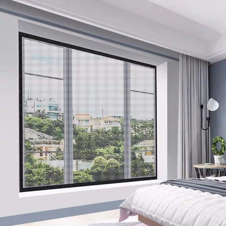 Hand pressing down a unisex anti-mosquito window screen, securing the self-adhesive insect barrier