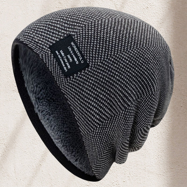 A stack of assorted color unisex thermal knit beanie hats for winter. Black, grey, navy, red, green.