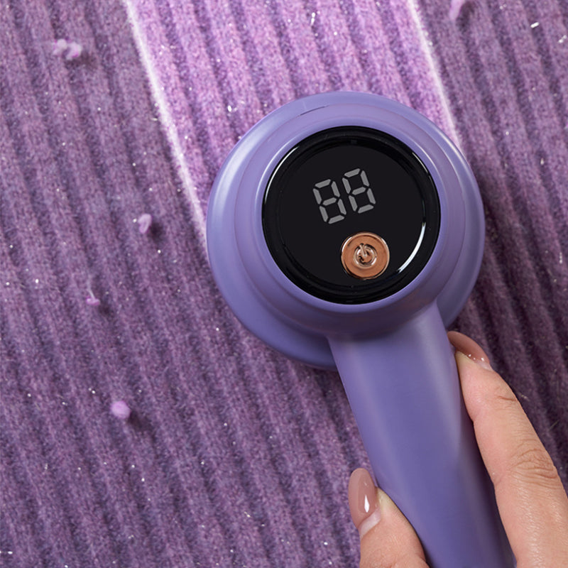 Fuzz remover for garments, held by hand, demonstrating ergonomic design and portable use.