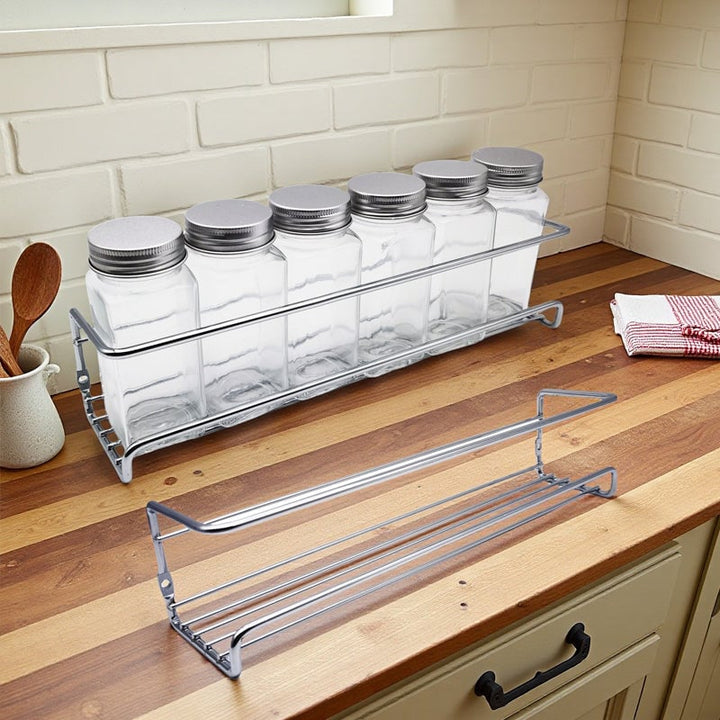 Spice rack for kitchen, black carbon steel, mounted near a stove for convenient access while cooking.