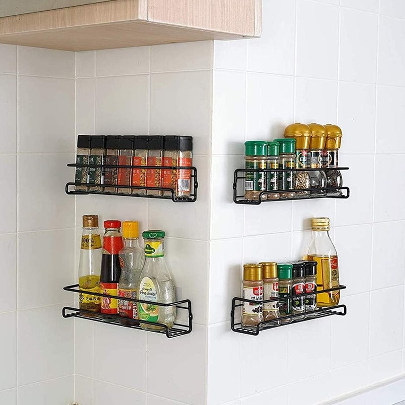 Close-up of a black carbon steel spice rack mounted on a kitchen wall, filled with spice jars.