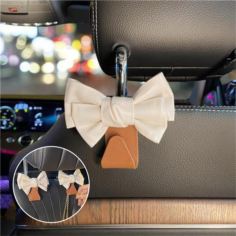 Close-up of bowknot car seat hook, pearl white, hanging from headrest for organization