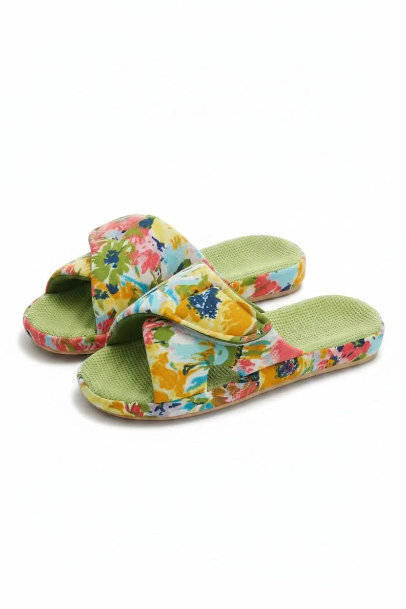 Woman's feet wearing comfortable adjustable open-toe slippers on a rug.