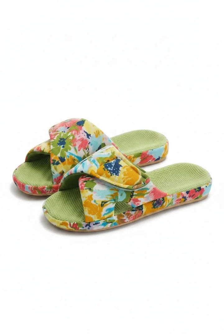 Woman's feet wearing comfortable adjustable open-toe slippers on a rug.