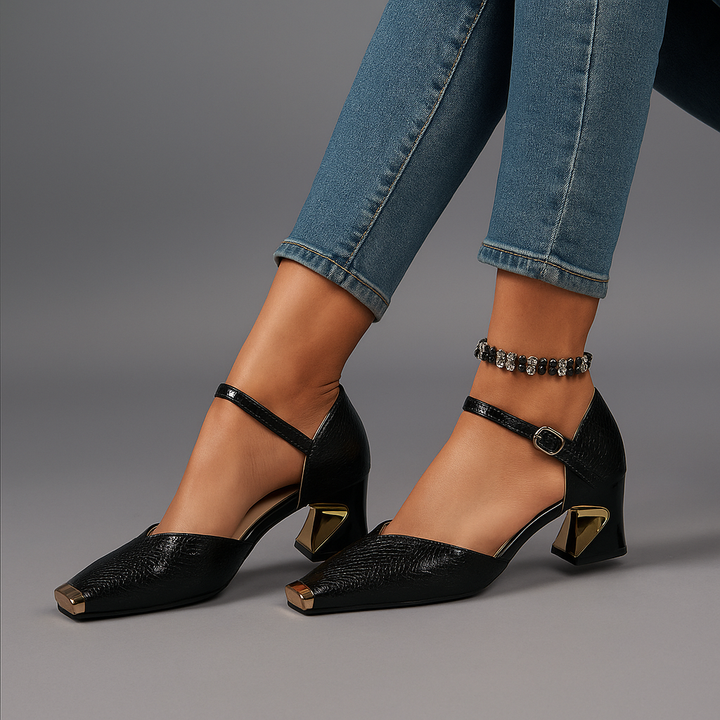 Close-up of a women's black croc-textured block heel with a shiny gold metal tip, party footwear