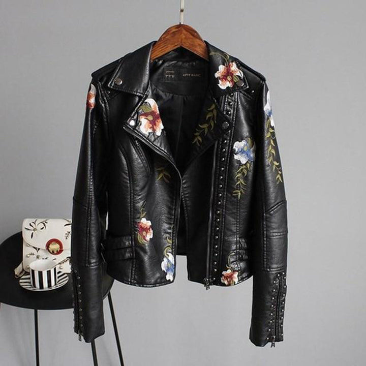 Women's black faux leather biker jacket with intricate floral embroidery, zip-up front, and studded details.