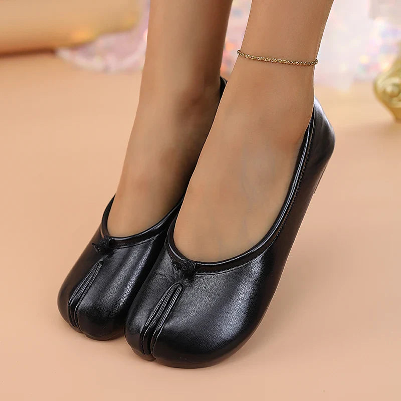 Black faux leather slip-on shoes for women, with an eye-catching split toe detail.