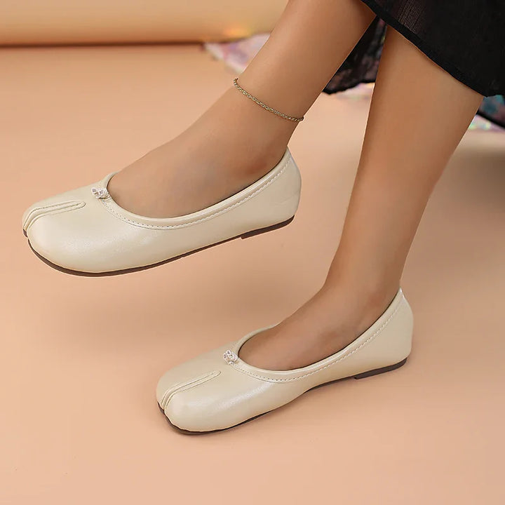 Casual women's shoes: black slip-on split toe flats with a modern design.