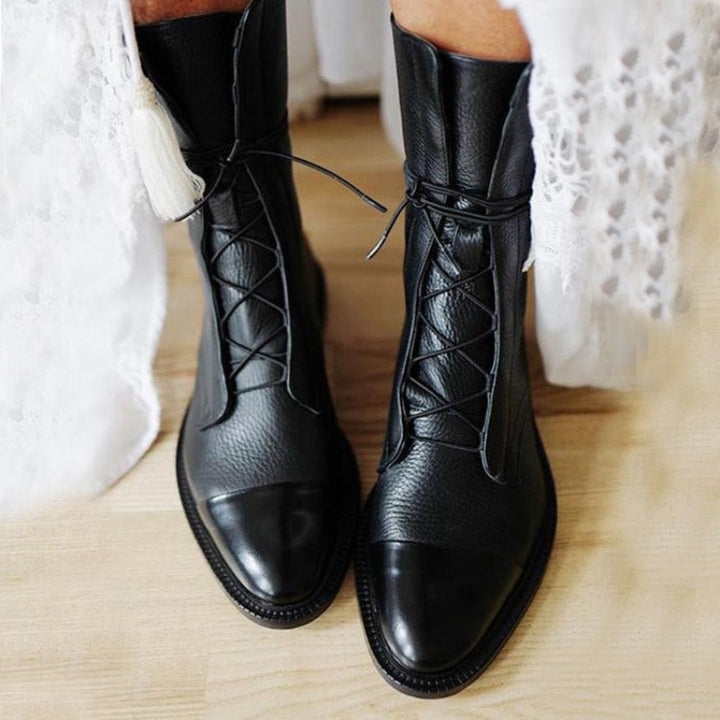 Close-up of women's brown leather combat boots, featuring classic lace-up design and ankle height.