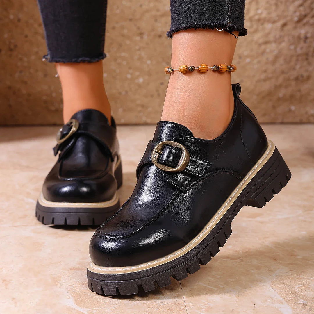 Side view of women's leather loafers with a sleek buckle, emphasizing the flat design.