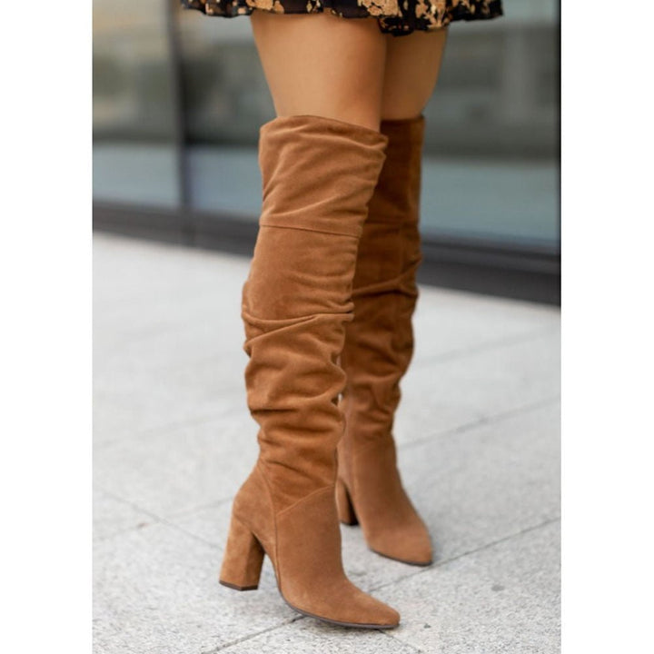 Close-up of a women's black slouchy over-the-knee boot, showcasing the high heel and pointed toe detail