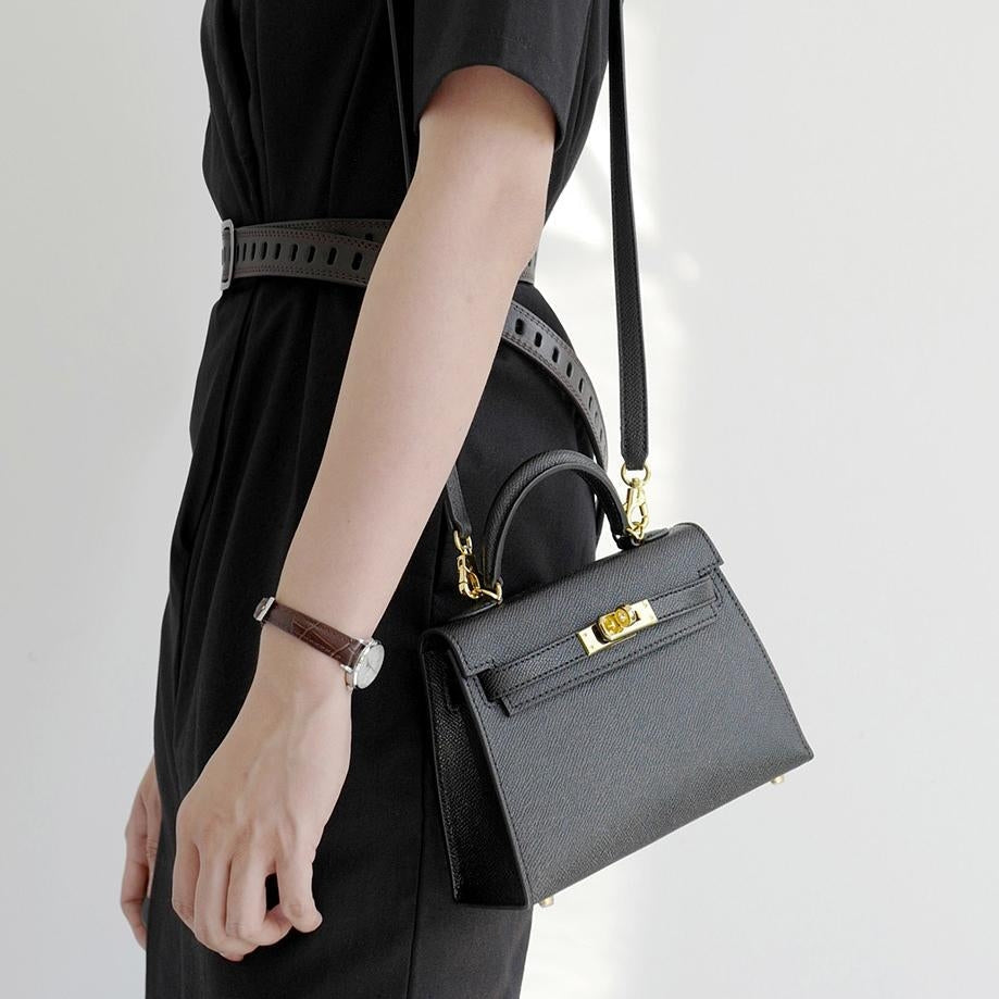Women's black top handle crossbody bag with gold turn lock. Structured vegan leather handbag, versatile fashion accessory.
