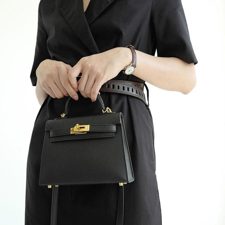 Women's versatile top handle crossbody bag featuring a secure gold turn lock. Structured design, perfect shoulder handbag.