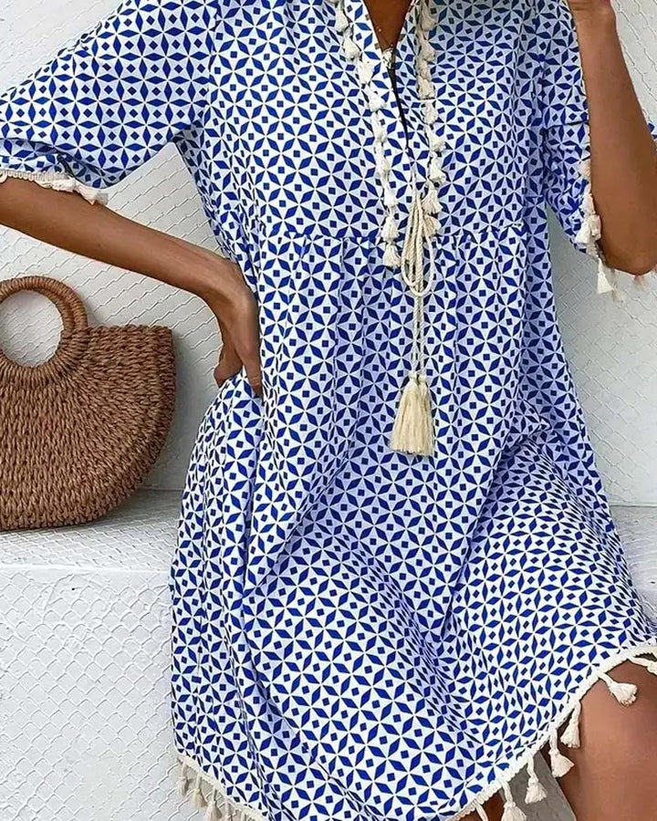 V-neck women's boho mini tunic dress with short sleeves, striking geometric print & decorative tassel hem.