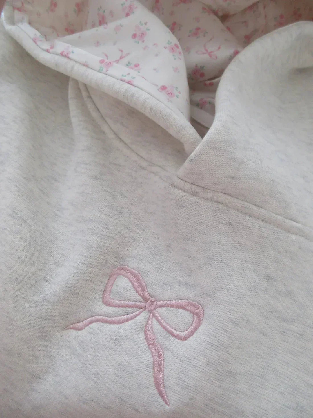 Stylish women's elegant hoodie featuring a decorative bow, relaxed fit, and front kangaroo pocket.