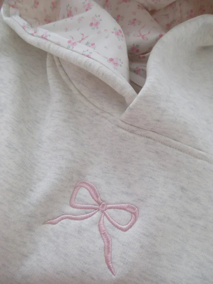 Stylish women's elegant hoodie featuring a decorative bow, relaxed fit, and front kangaroo pocket.