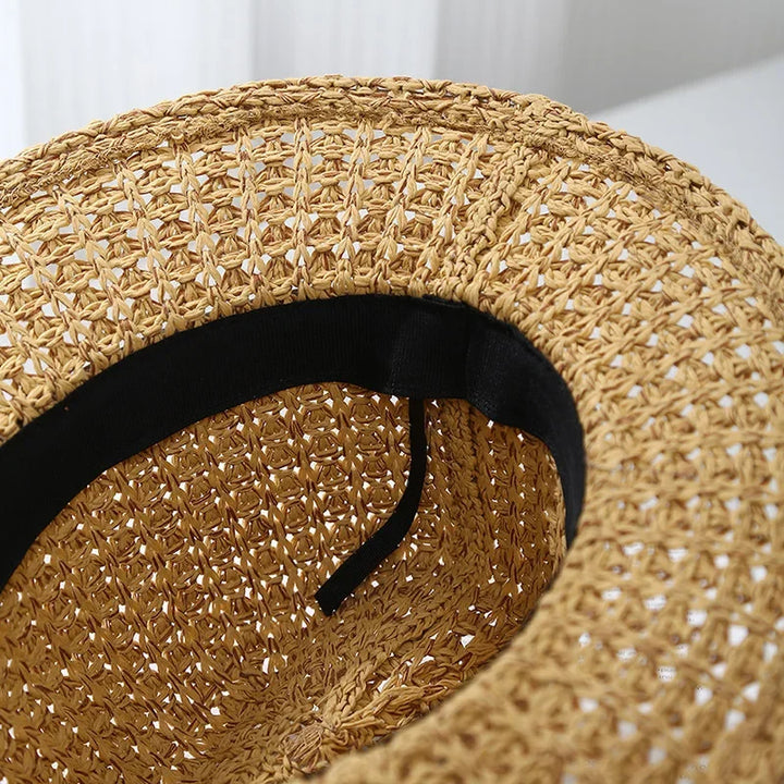 Front view of a women's beautiful woven fedora sun hat, highlighted by its faux leather detail.