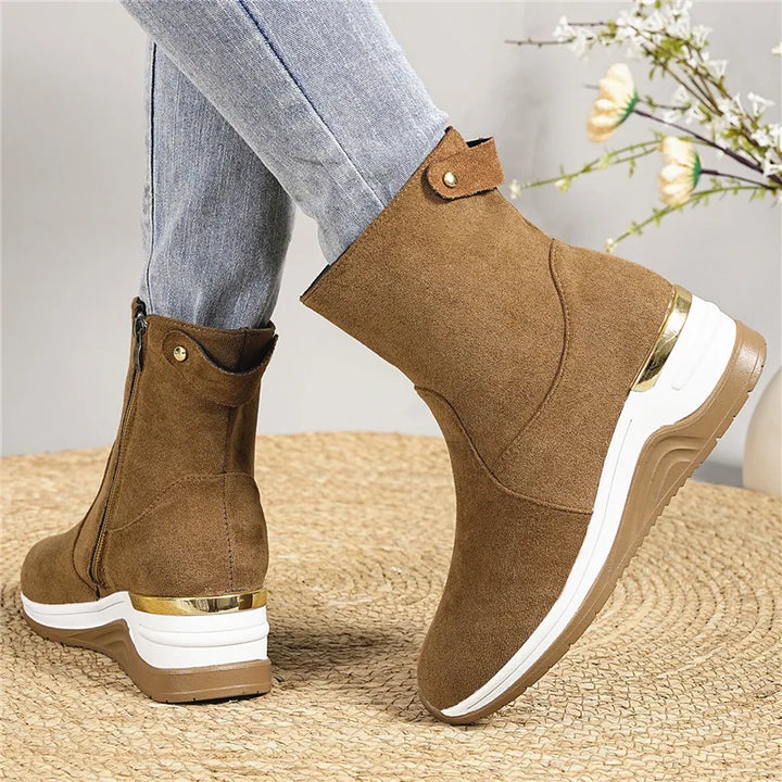 A stack of women's suede ankle boots in various shades, all offering orthopedic comfort.