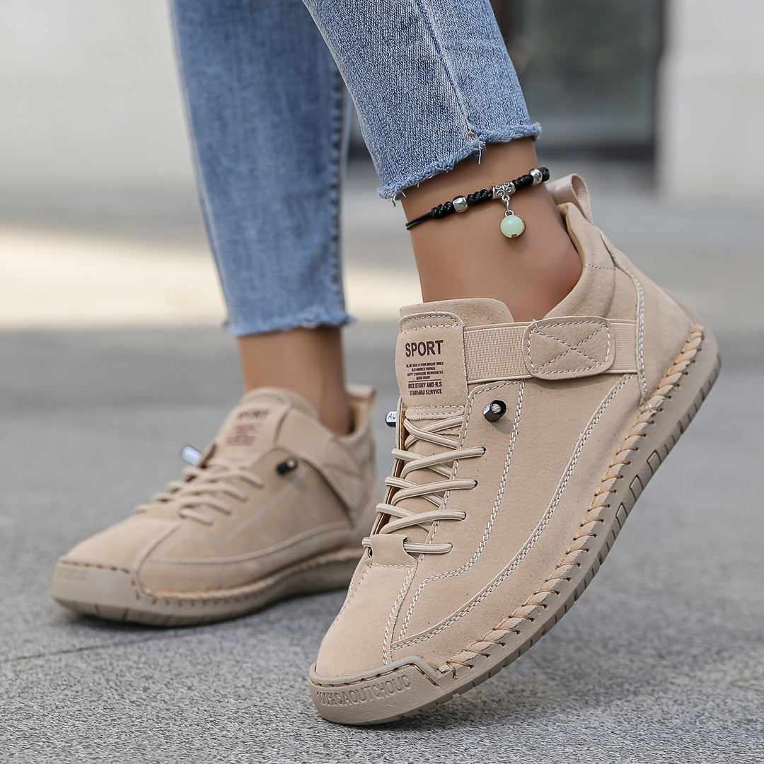 Side view of women's flat lace-up sneakers with intricate stitch detail, designed for comfortable everyday wear.