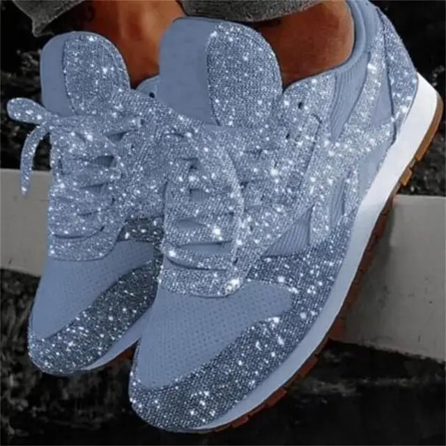 Close-up of women's sparkling glitter sneakers with white laces. Dazzling texture, trendy casual shoes.