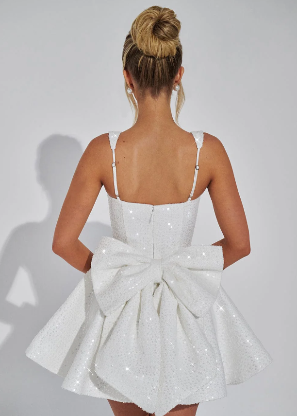 Side profile of a women's pink sequin backless bow mini dress, highlighting its flattering A-line silhouette.