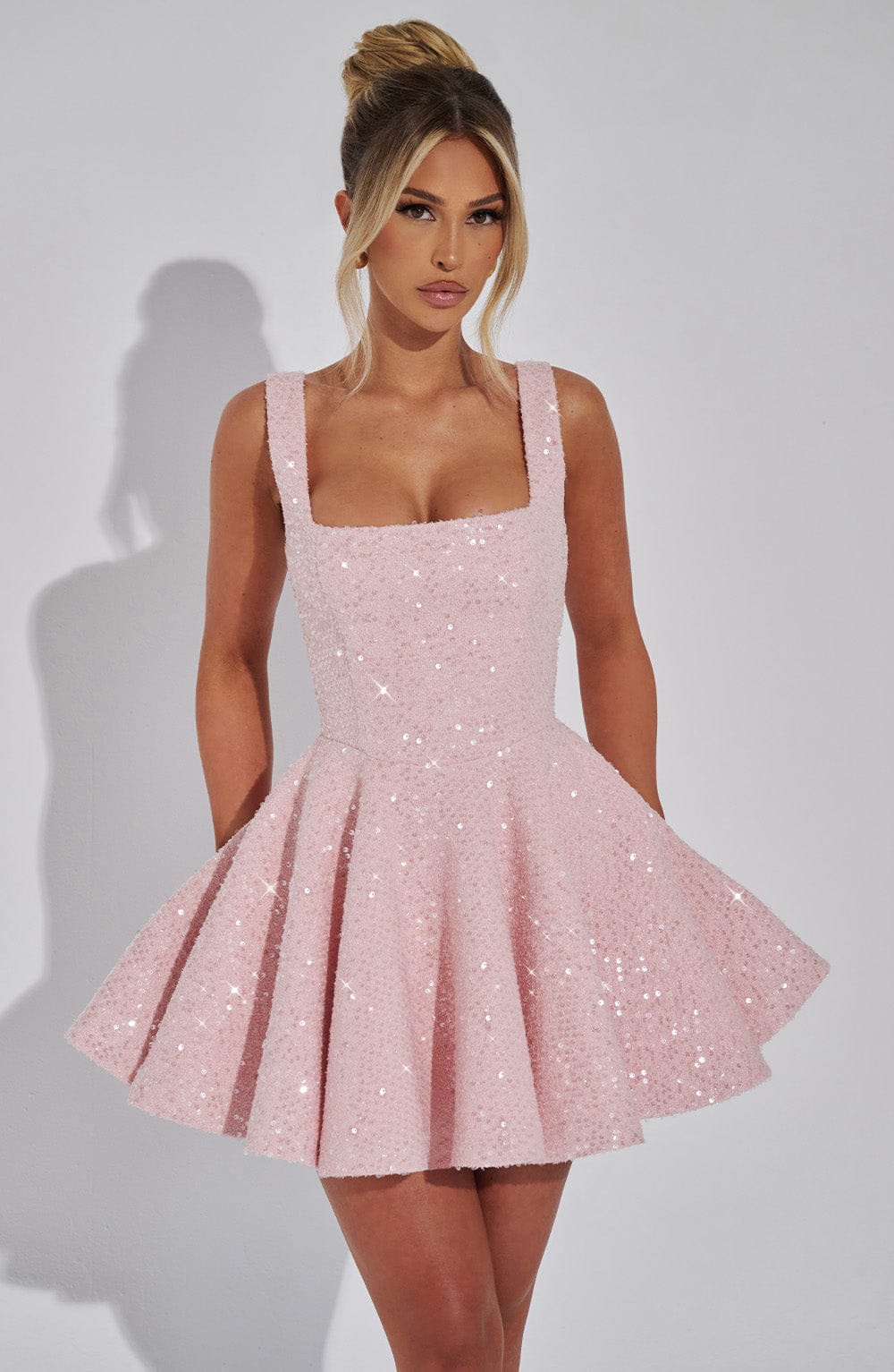 Close-up of the shimmering sequin fabric on a women's dazzling backless bow mini dress.